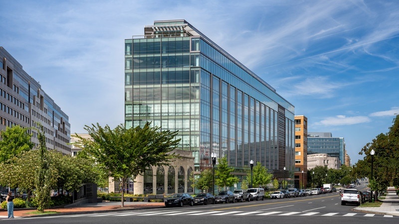 The glass facade of 20 Mass Ave on a bustling street corner in Washington, D.C. near Union Station