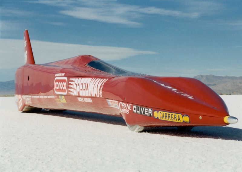 A red streamliner race car in the desert. 