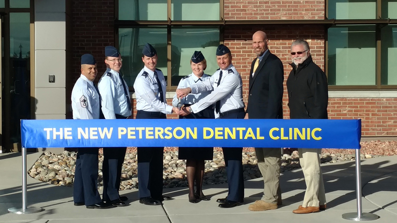 Dignitaries cutting a large ribbon at the new Peterson Dental Clinic, designed by LEO A DALY